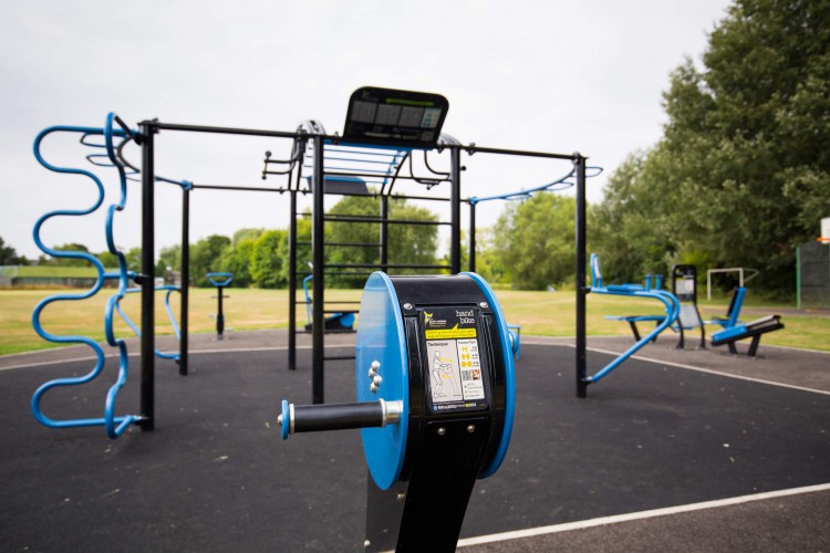 blue and black climbing frame and exercise machines in an open grassy area 