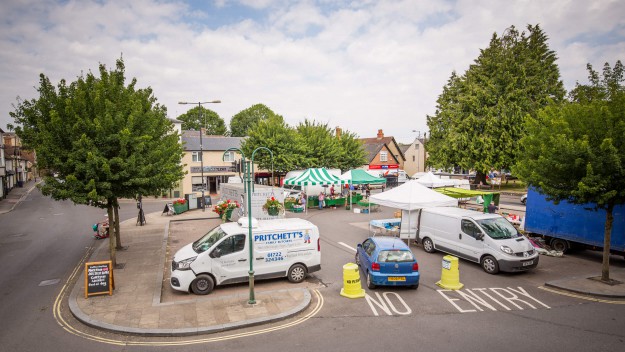 vans and stalls set up in a car park which has a few trees around it